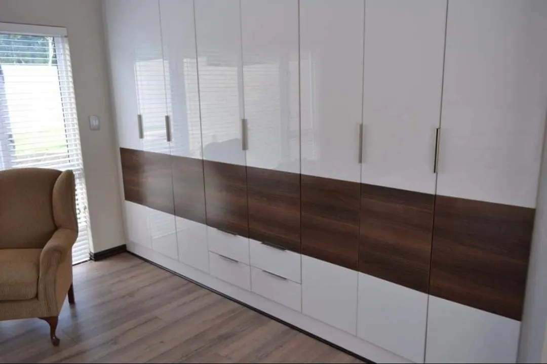 High-gloss white wardrobes with a walnut band and drawers
