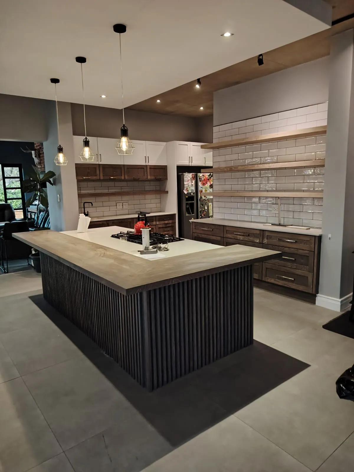 Kitchen with a dark oak slatted island, wide timber counter, white subway tiles and floating oak shelves